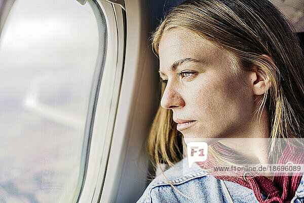 Young woman looking out of airplane window