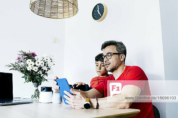 Father sharing tablet PC with son at home