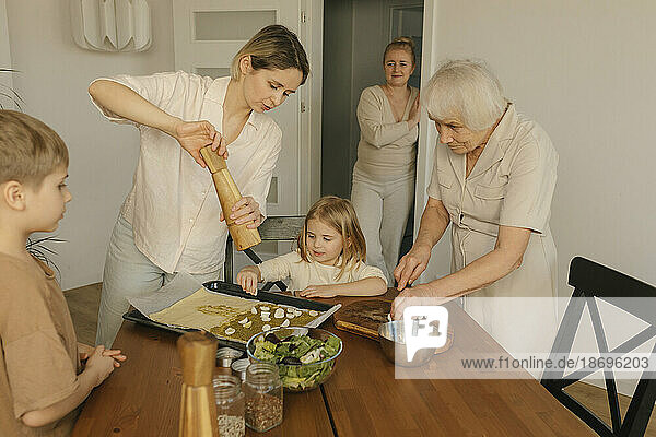 Frau streut Pfeffer auf das Essen einer Familie zu Hause