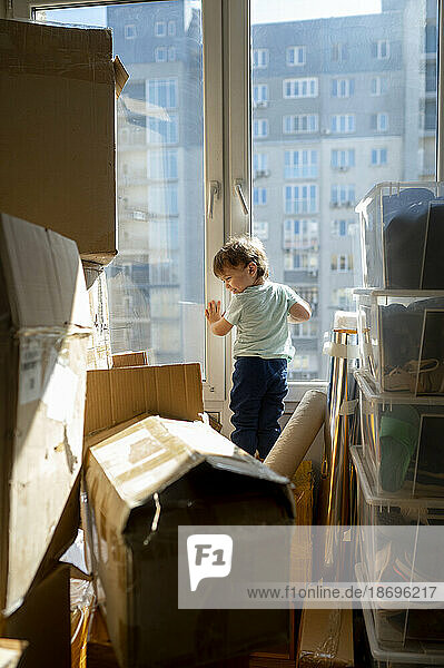 Junge steht zu Hause inmitten von Kartons