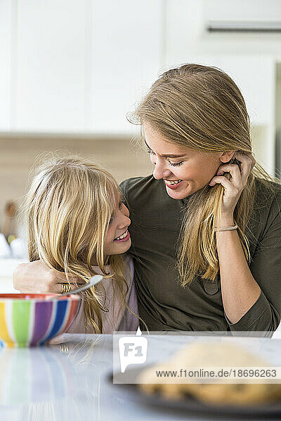 Happy mother with arm around daughter at home