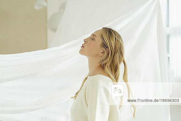 Frau mit geschlossenen Augen durch einen weißen  durchscheinenden Vorhang