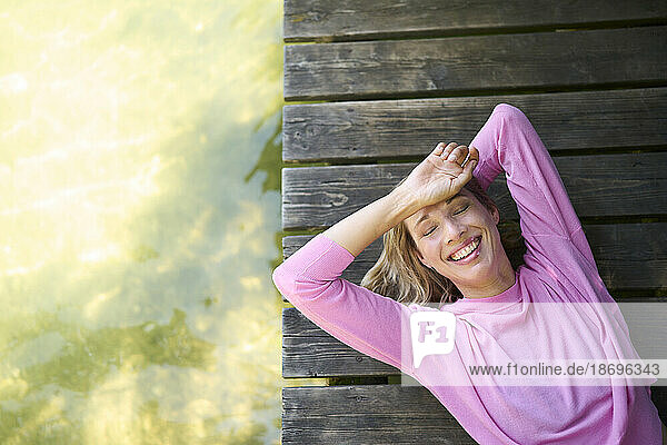 Happy mature woman lying down on boardwalk