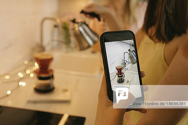 Frau fotografiert zu Hause Filterkaffee per Smartphone