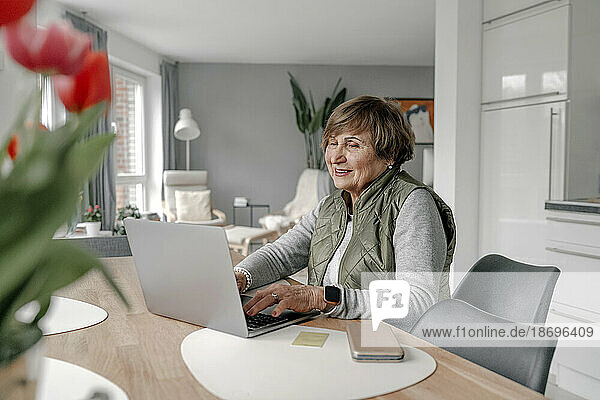 Ältere Frau kauft zu Hause per Laptop online ein