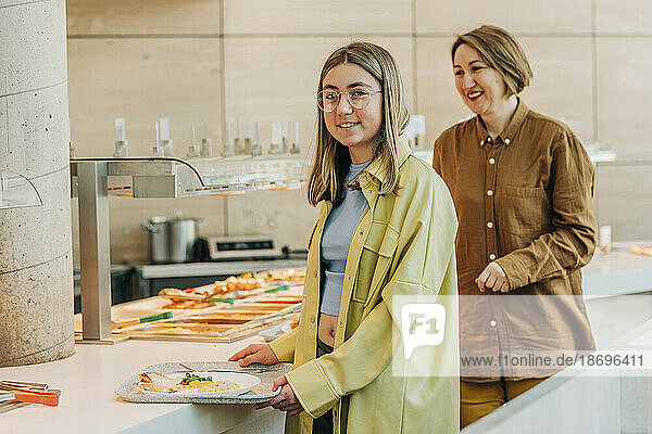 Smiling mother and daugther taking food at buffet in cafe