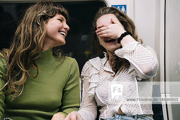 Smiling woman laughing by female friend in subway