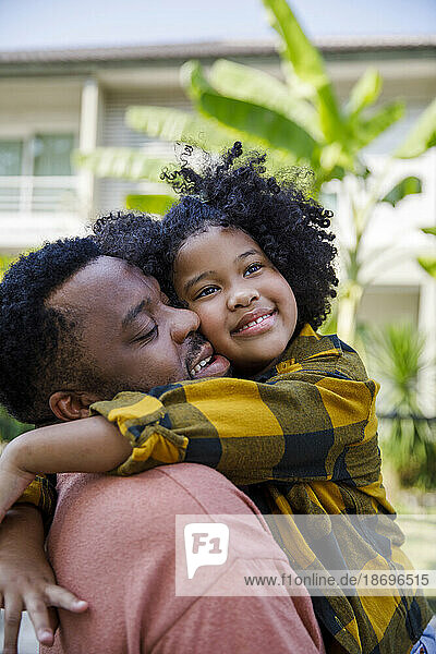 Smiling man embracing daughter with curly hair
