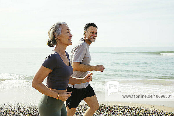 Smiling mature couple running at seashore