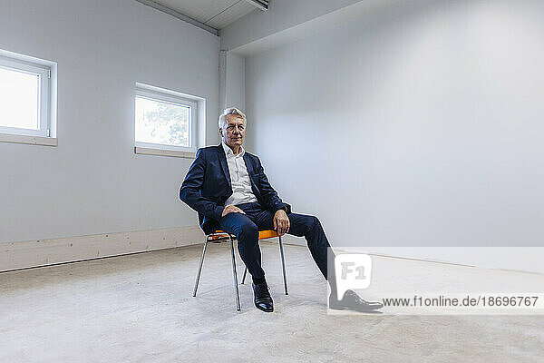 Leitender Geschäftsmann sitzt auf einem Stuhl im Zimmer