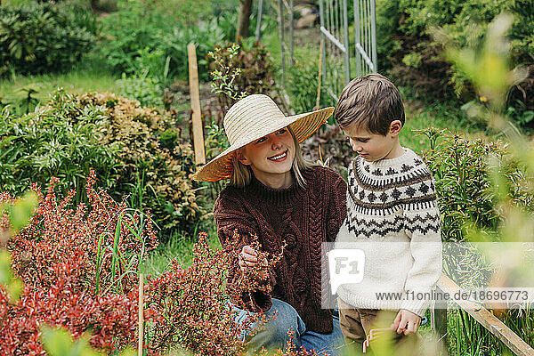 Smiling mother showing flower to son in garden