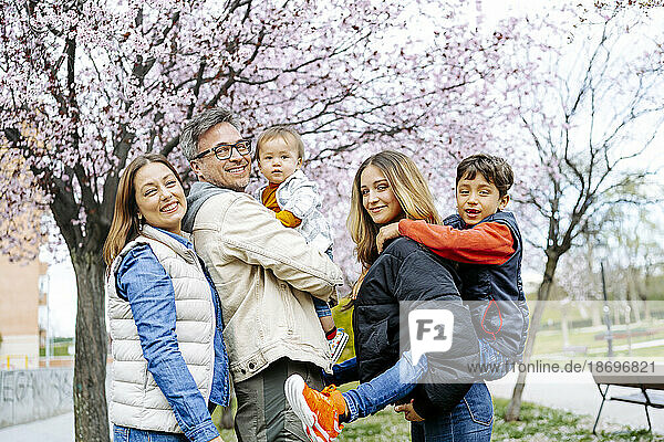 Happy family standing in front of cherry blossom tree