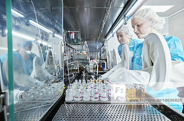 Scientists working with chemical bottles inside microbiological safety cabinet