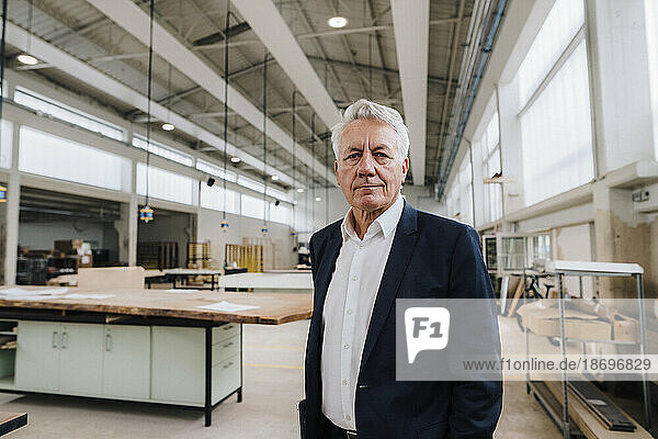 Senior businessman standing on production floor in factory