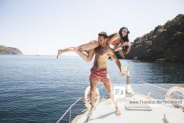 Shirtless man having fun with girlfriend on yacht at vacation