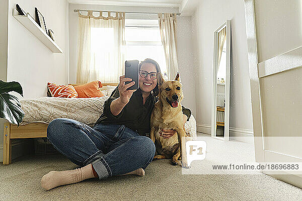 Frau macht Selfie mit Hund  der zu Hause sitzt