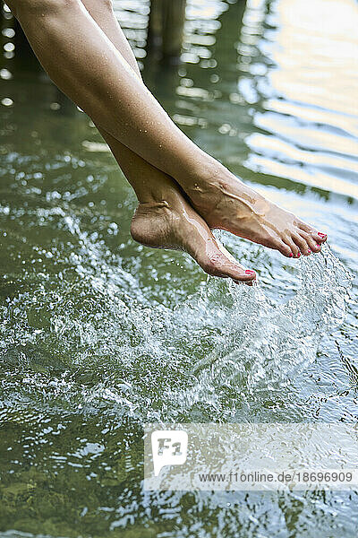 Woman splashing water with feet in lake
