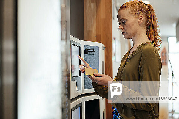 Redhead woman operating ATM machine
