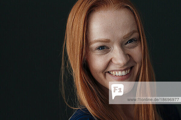 Cheerful redhead woman against black background