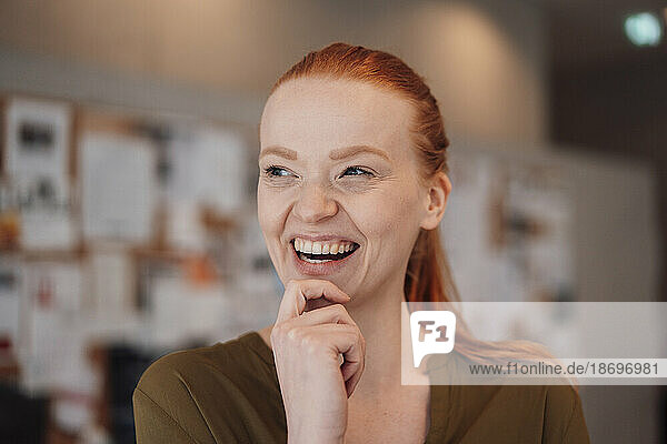Happy redhead woman with hand on chin