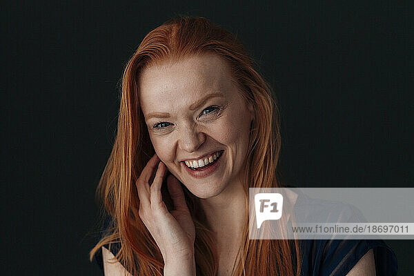 Happy redhead woman against black background