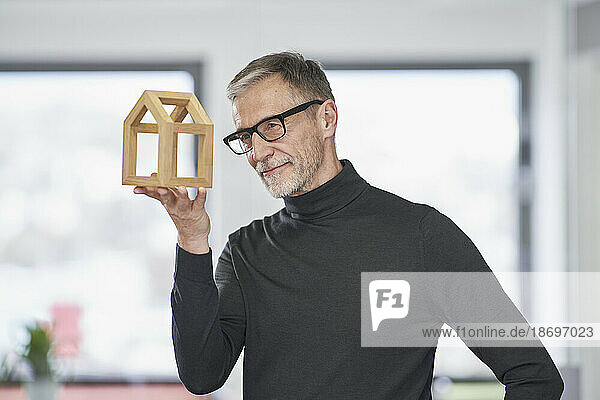 Senior architect looking at model house in office