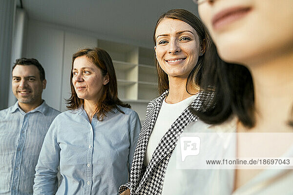 Portrait of smiling businesswoman with colleagues in office