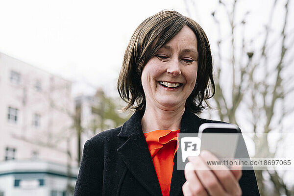 Lächelnde Frau im Blazer mit Smartphone