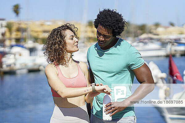 Woman showing smart watch to boyfriend at harbour
