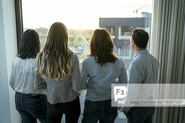 Rear view of business team looking out of window in office
