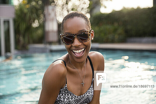 Fröhliche Frau mit Sonnenbrille am Pool des Resorts