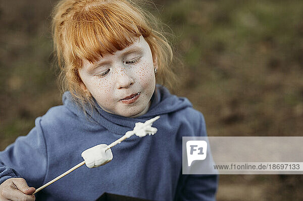 Redhead girl eating roasted marshmallow