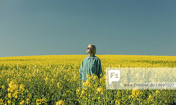 Woman standing amidst flowers in rapeseed field