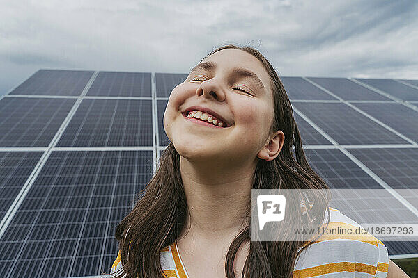 Glückliches Mädchen mit geschlossenen Augen vor Sonnenkollektoren