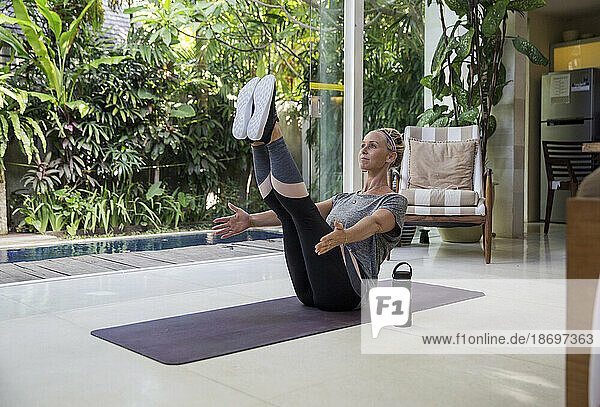 Woman doing abdominal exercise on yoga mat at home