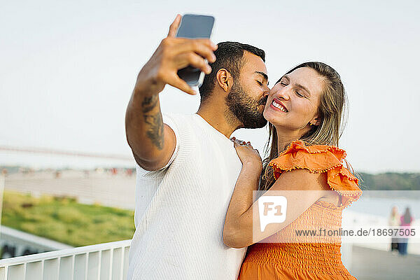 Man kissing and taking selfie with pregnant woman