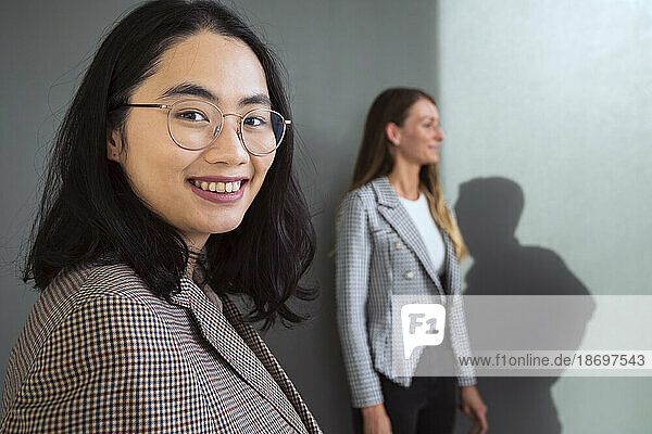 Porträt einer lächelnden Geschäftsfrau mit einem Kollegen im Hintergrund