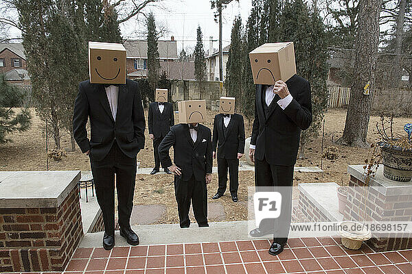 Five box-headed men in tuxedos stand in a residential yard; Lincoln  Nebraska  United States of America