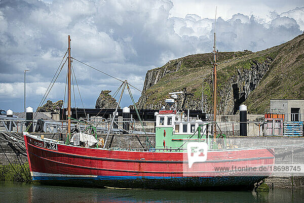Close-up view of a fishing boat docked in the Sherkin Island harbour with the sea cliffs in the background; West Cork  Ireland