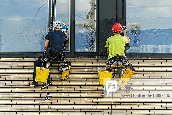 Zwei Männer putzen Fenster eines Bürogebäudes