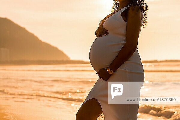 Schwangere Mutterschaft latin Frau am Strand bei Sonnenuntergang  Mutterschaft Konzept. Frau Silhouette