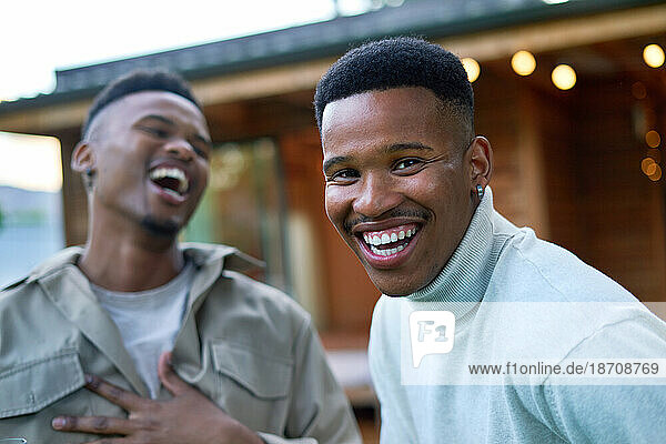 Portrait happy young gay male couple laughing on patio