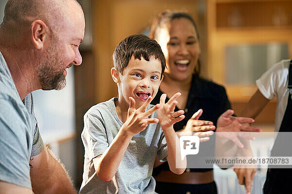 Portrait happy boy with Down Syndrome clapping with family