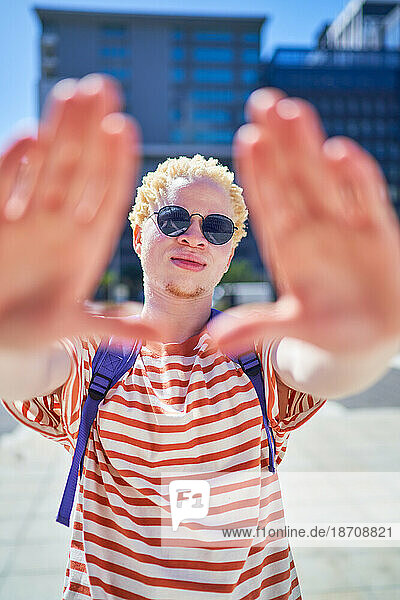 Portrait cool young man gesturing finger frame in sunny city