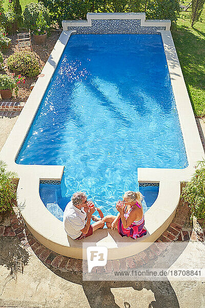 Älteres Paar entspannt sich und trinkt Cocktails am sonnigen Swimmingpool