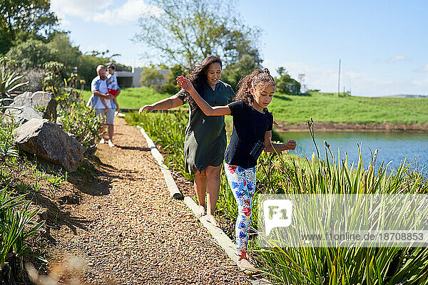 Mother and daughter balancing  walking on footpath logs