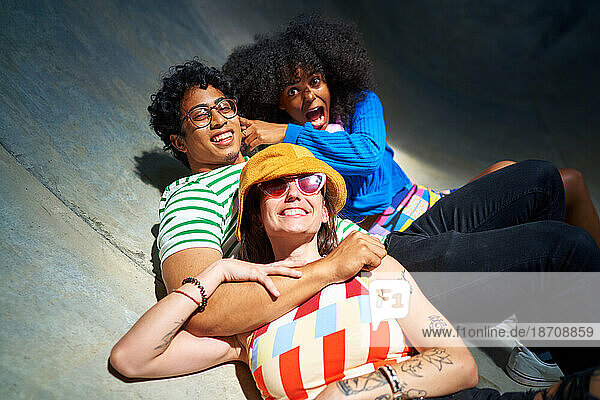 Portrait happy  carefree young friends laying on sports ramp