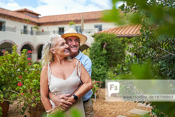 Happy senior couple hugging in garden outside summer villa