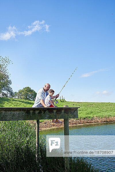 Father and son fishing on sunny summer lakeside dock