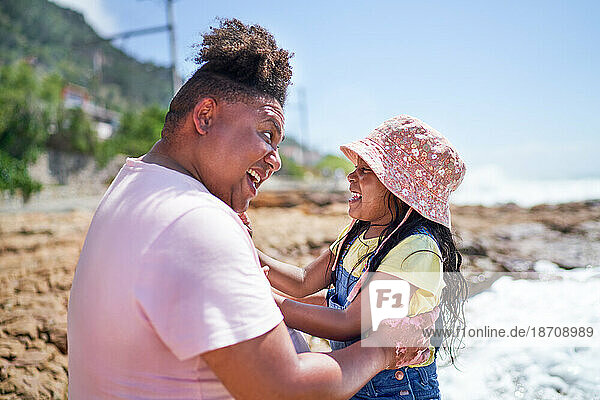 Happy father and daughter laughing on sunny summer beach